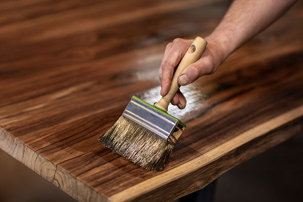 Photo of WOCA Finishing Oil being applied to wooden table with a paint brush.